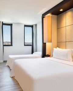 a hotel room with two beds and two windows at Hotel Barcelona Condal Mar, Affiliated by Meliá in Barcelona +39 photos