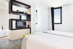a hotel room with two beds and a tv at Hotel Barcelona Condal Mar, Affiliated by Meliá in Barcelona