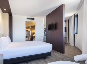 a bedroom with a white bed and a tv at Hotel Barcelona Condal Mar, Affiliated by Meliá in Barcelona