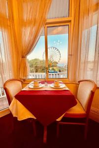 a table with chairs and a window with a ferris wheel at SmartsWay Hotel & Wellness in Eastbourne