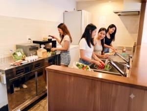 a group of women standing in a kitchen preparing food at BANDE Hotel in Namba in Osaka