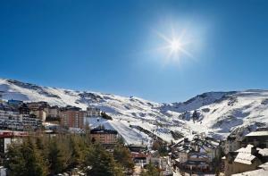 a city with a snow covered mountain in the background at Meliá Sol y Nieve in Sierra Nevada