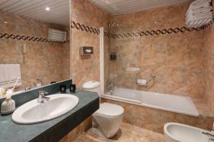 a bathroom with a sink and a toilet and a tub at Meliá Sol y Nieve in Sierra Nevada