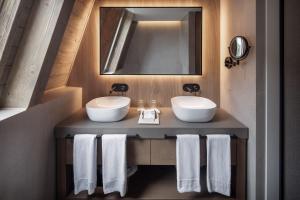 a bathroom with two sinks and a mirror and towels at MiM Baqueira member of Meliá Collection in Baqueira-Beret