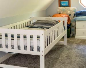 a white crib in a room with a bed at Blackberry Bunkhouse in Ashford
