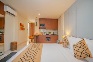 a bedroom with a white bed and a kitchen at Anandani Suites in Canggu
