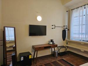 a room with a table and a television on the wall at BKL Hotel Oaxaca in Oaxaca City