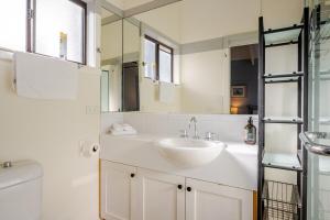 a white bathroom with a sink and a mirror at The Mariner - Oceanfront Living in Falmouth +25 photos