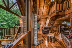 a living room with a staircase in a log cabin at Absolute Bearadise cabin in Sevierville