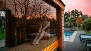 a man sitting on a window in a swimming pool at Manawa Retreat in Whitecliffs