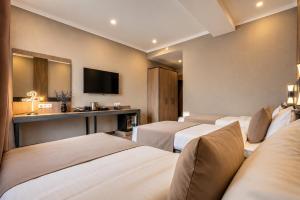 a hotel room with three beds and a television at Sara Hotel Bishkek in Bishkek