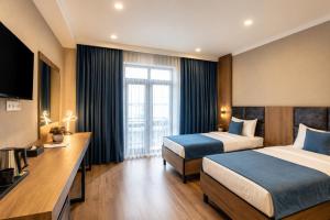 a hotel room with two beds and a television at Sara Hotel Bishkek in Bishkek