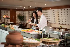 a man and a woman preparing food in a buffet at Koulen Central Premier Suites in Siem Reap