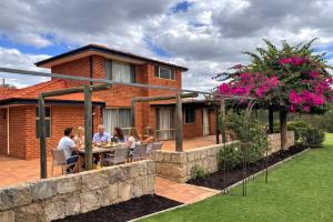 a group of people sitting at a table outside of a house at Sittella's Vineyard Residence in Herne Hill