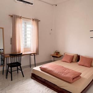 a bedroom with a bed and a table and a desk at Nhà của Buôn in Buon Ma Thuot