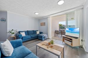 a living room with a blue couch and a tv at Moana Condo | Close to Beach in Caloundra