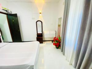 a bedroom with a bed and a mirror and a window at Hotel Kandy Village Inn in Kandy +1 photo