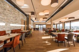 a restaurant with tables and chairs and windows at Hotel TheGreen in Cologne
