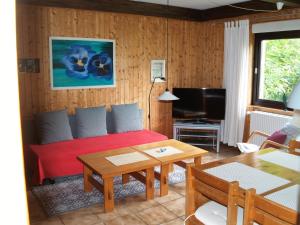 Sala de estar con cama roja y mesa en Ferienwohnung An der Innerste en Wildemann