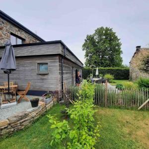 a person standing in a garden next to a house at Au doux gîte in Bras-Haut