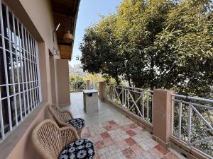 a balcony with wicker chairs and a table and trees at LRX Retreats in Chaubattia