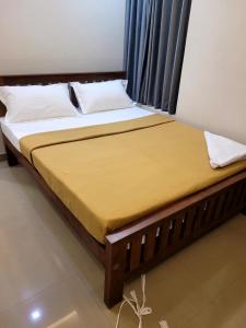 a bed with a wooden frame with a yellow mattress at Hotel Grand Illam in Ernakulam