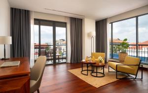 a living room with a table and chairs and windows at Koulen Central Premier Suites in Siem Reap