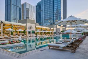 a pool with chairs and umbrellas in a city at Hilton Tashkent City in Tashkent
