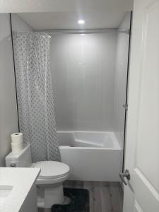 a white bathroom with a toilet and a shower at Peniel Place in Airdrie +9 photos