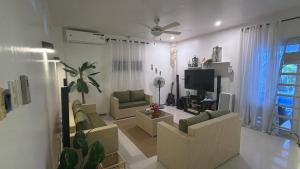 a living room with couches and a flat screen tv at The beach house, Baroro Beachfront Villa in Bacnotan