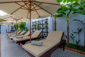 a row of chaise lounges with umbrellas at Raksmey Angkor Boutique in Siem Reap