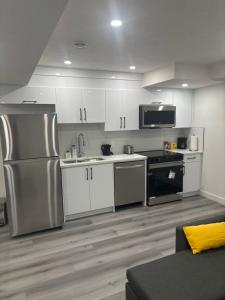 a kitchen with white cabinets and a stainless steel refrigerator at Peniel Place in Airdrie