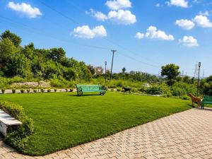 a park with a green bench and animals in a field at The hotel golden crown in Baddi +1 photo