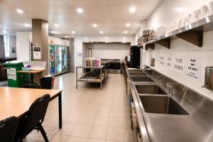 a kitchen with a row of sinks and a counter at Perth City Backpackers Hostel - note - Valid passport required to check in in Perth