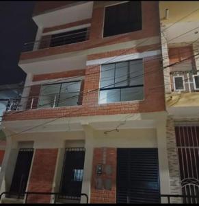 ein Backsteingebäude mit Fenstern und einem Balkon in der Unterkunft Edificio Las Palmas in Tumbes