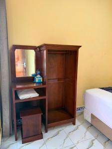 a wooden book shelf with a mirror next to a bed at Amita Homestay in Tambolaka Airport