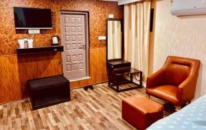 a room with a bed and a chair and a television at MGallery in Srinagar