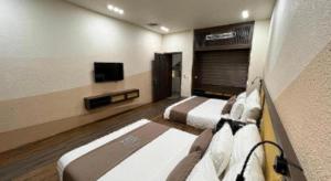 a hotel room with two beds and a television at Viettrekking Sapa in Lo Sui Tong
