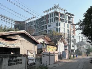 a tall white building in front of a building at DM udon in Udon Thani
