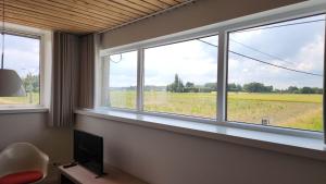 a room with three windows with a view of a field at Logies De Vlaschaerd in Heule
