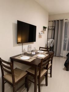 a dining room table with chairs and a television on the wall at Jtower residences mandaue 27flr in Mandaue City