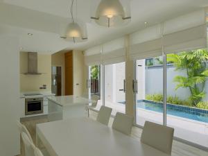 a kitchen and dining room with a white table and chairs at 5 Minutes to Naiharn Beach, Private, Quiet and Cozy in Nai Harn Beach