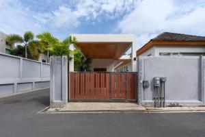 a house with a wooden gate and a fence at 5 Minutes to Naiharn Beach, Private, Quiet and Cozy in Nai Harn Beach