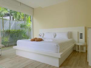 a bedroom with a white bed with a stuffed animal on it at 5 Minutes to Naiharn Beach, Private, Quiet and Cozy in Nai Harn Beach +20 photos