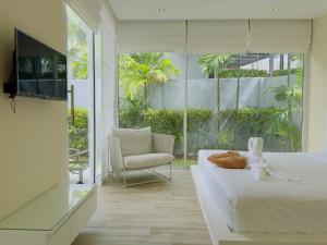 a bedroom with a bed and a chair and a television at 5 Minutes to Naiharn Beach, Private, Quiet and Cozy in Nai Harn Beach