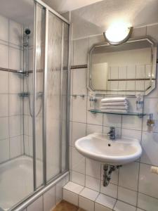 La salle de bains est pourvue d'un lavabo, d'une douche et d'un miroir. dans l'établissement NOEL Hotel-Restaurant, à Seevetal