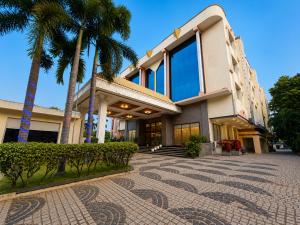 a building with palm trees in front of it at Zip By Spree Hotels Surabi International Vellore in Vellore
