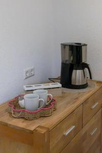 a coffee maker and two cups on a wooden dresser at Ferienwohnung Land Leben in Ziertheim