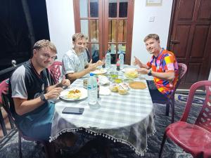 three men sitting at a table eating food at Lumora Resort in Horuwila