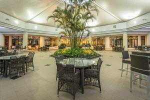 un hall avec des tables, des chaises et un palmier dans l'établissement Hotel Vip Grand Maputo, à Maputo